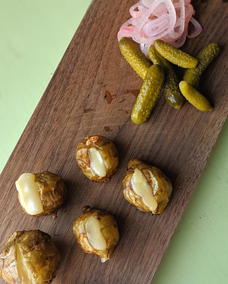 Roasted Sunchokes Filled with Melted Raclette, Served with Cornichon and Pickled Shallots