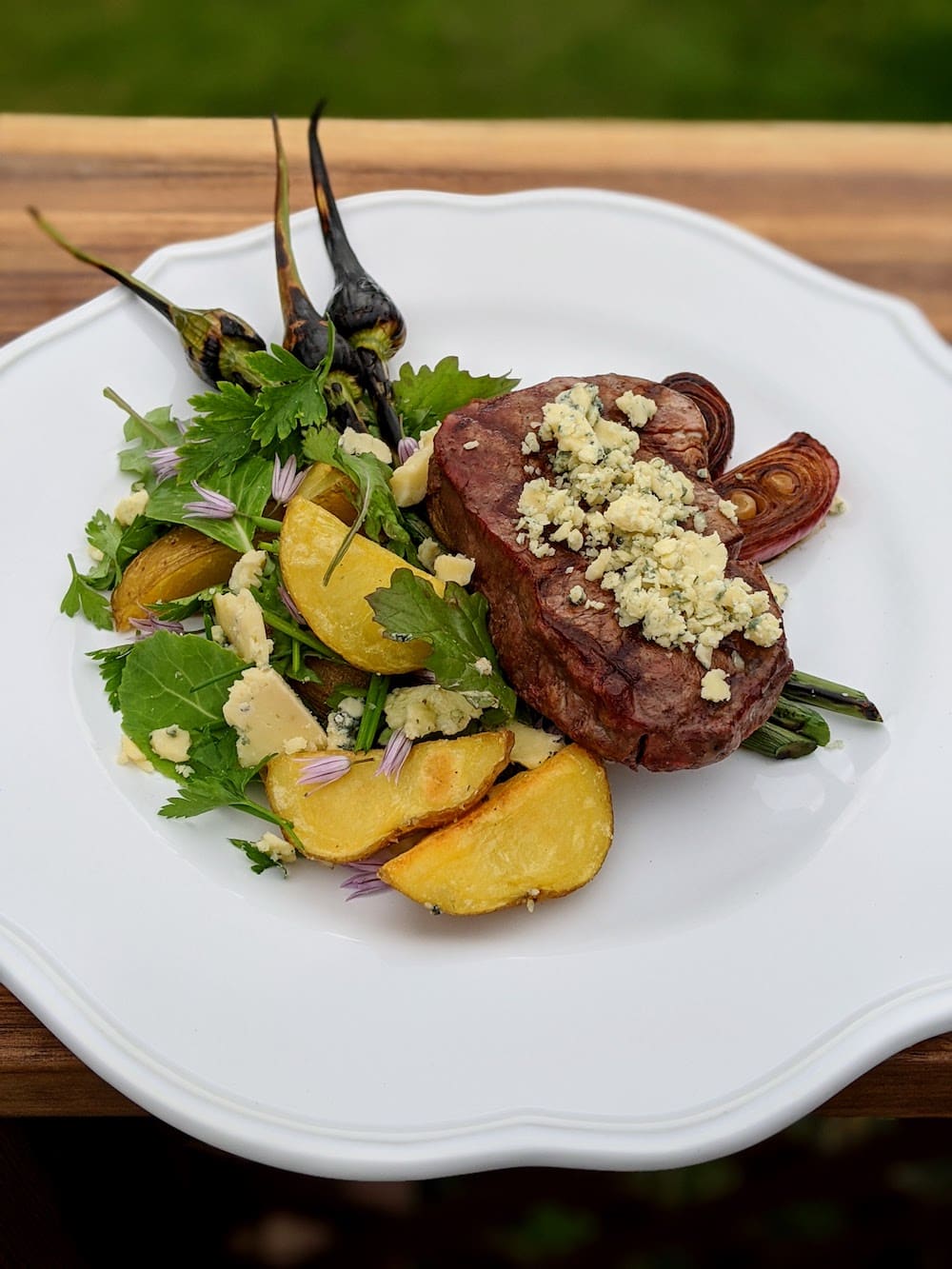 Filet, Stilton, Roasted Potato Salad, Balsamic Onions A Plate with Filet Steak Topped with Stilton and Roasted Potato Salad with Chive, Balsamic Roasted Onions and Garlic Scapes